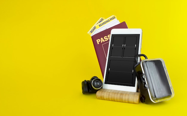 Passaporti e biglietti con valigia su sfondo giallo.