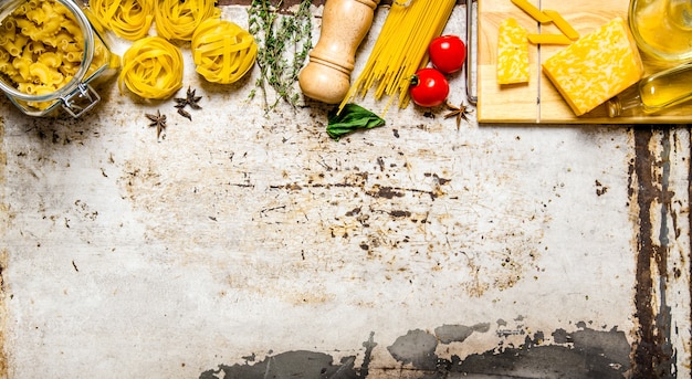 Pasta background. Dry pasta with vegetables, mushrooms, cheese and herbs. On rustic background.  Free space for text . Top view