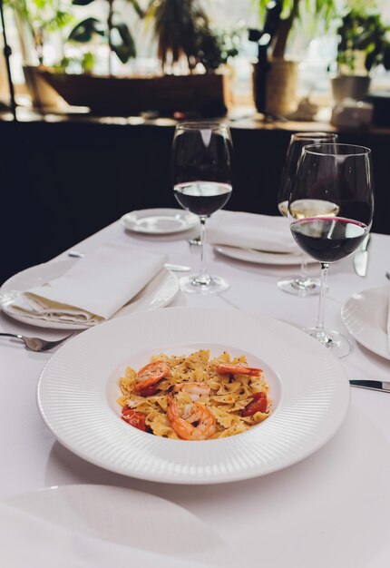 Pasta bavette met gebakken garnalen bechamelsaus muntblad knoflook tomaten chili op witte plaat bovenaanzicht Italiaanse keuken