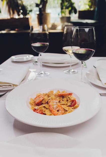 Pasta bavette met gebakken garnalen bechamelsaus muntblad knoflook tomaten chili op witte plaat bovenaanzicht Italiaanse keuken