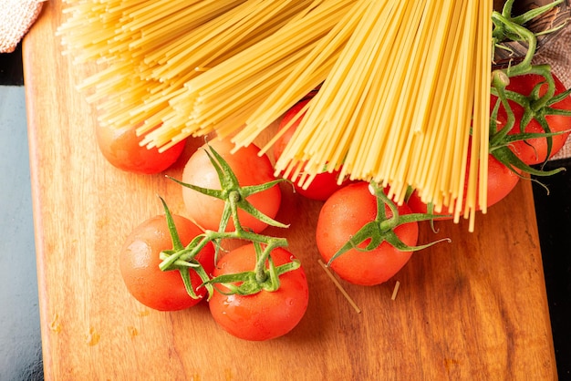 Pasta beautiful details of red tomatoes and strands of raw spaghetti over rustic wood top view