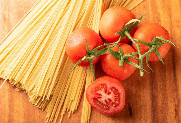 Pasta beautiful details of red tomatoes and strands of raw spaghetti over rustic wood top view