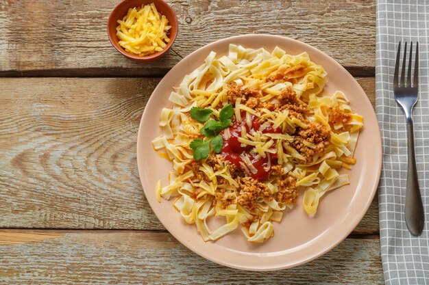 Pasta bolognese in tomaat gegarneerd met kruiden en kaas in een bord op een houten tafel