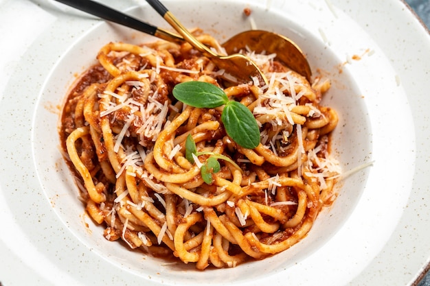 Pasta bolognese with tomato and meat mince sauce served in a plate with parmesan cheese. Traditional italian dish.