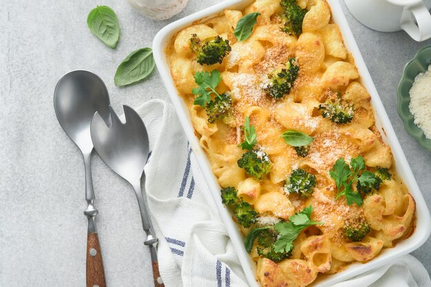 Photo pasta broccoli casserole baked mac and cheese with broccoli cream sauce and parmesan on gray light concrete table background healthy or baby food american casserole top view copy space