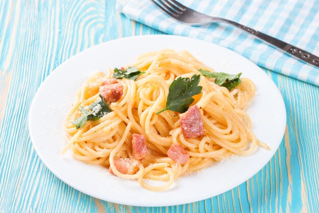 Pasta Carbonara met ham en kaas op blauwe houten ondergrond. Bovenaanzicht.