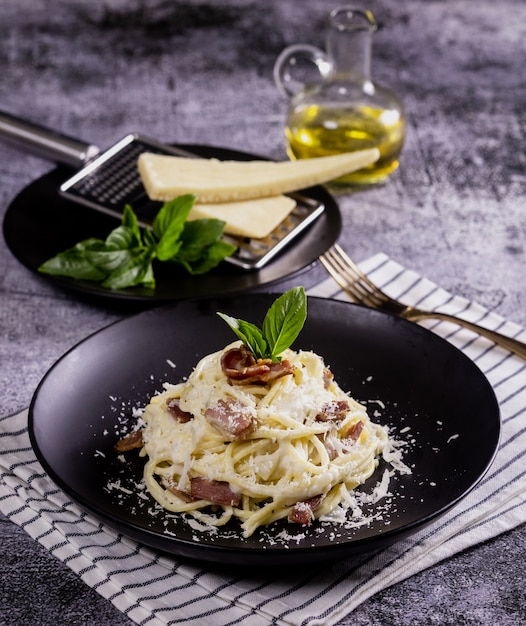 Pasta carbonara. spaghetti met spek, peterselie en parmezaanse kaas. pasta carbonara op zwarte plaat met parmezaanse kaas. italiaans eten.