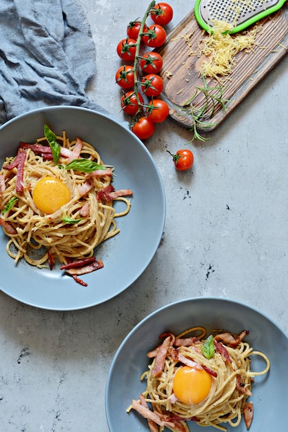 Pasta carbonara with bacon and parmesan in gray plates on the table, restaurant serve