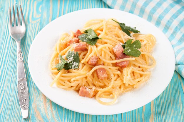 Pasta Carbonara with ham and cheese on blue wooden suface