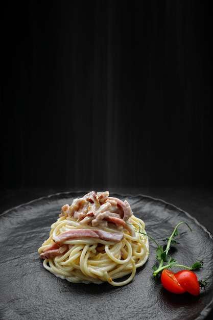 Pasta Carbonara with tomatoes on a black plate