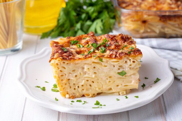 Photo pasta casserole bechamel sauce topped with melted mozzarella cheese and served in a white baking dish on a table (turkish name; firinda makarna or firin makarna)