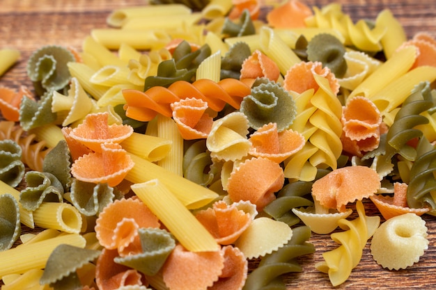 Pasta colorata, colorful spaghetti, macaroni, pasta on wooden background close up