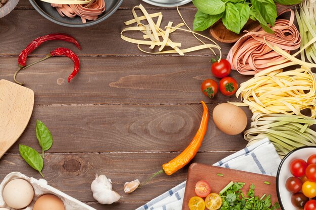 Pasta cooking ingredients and utensils on wooden table. Top view with copy space