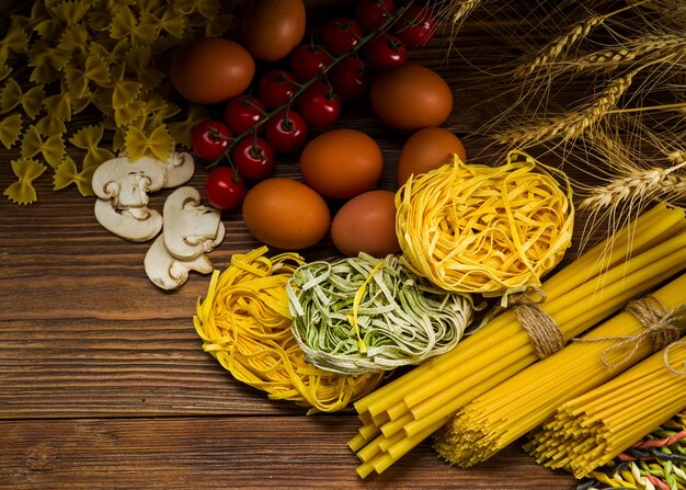 pasta of different types in raw form lies on the table decorated with ingredients for pasta