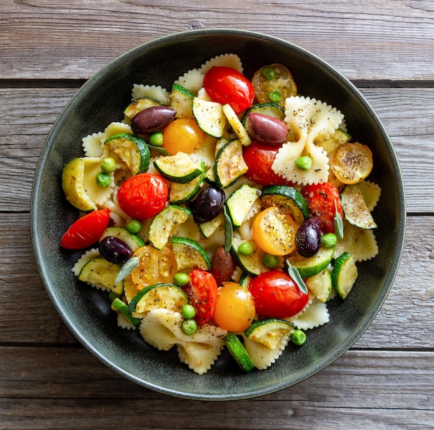 Pasta farfalle with tomatoes zucchini peas Kalamata olives and sage Healthy eating Vegetarian food