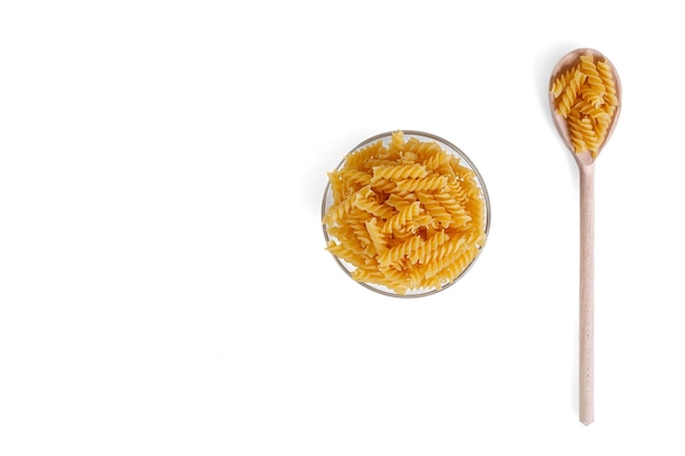 Pasta in the form of a spiral on a plate spoon texture on a white background