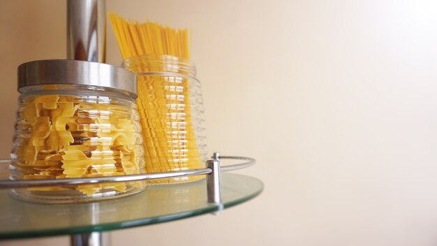 Pasta in a glass jar on light background. Free space for text