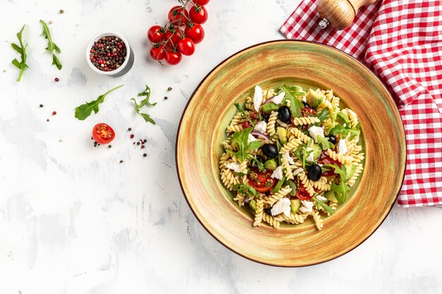 Pasta Greek salad with tomato, avocado, black olives, red onions and cheese feta. fresh, salad, banner, menu, recipe. Healthy food