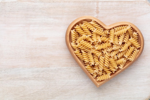 Pasta in een hartvormige houten kom