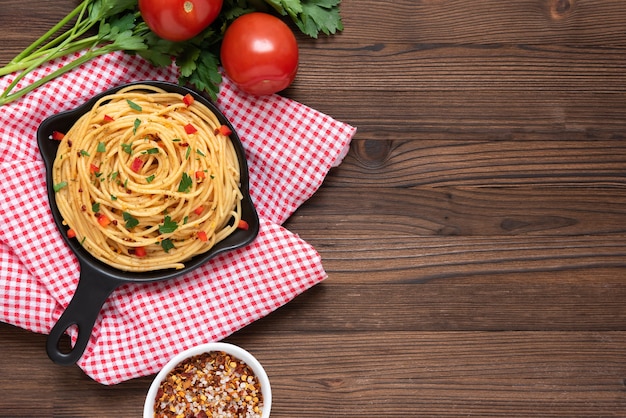 Pasta in een koekenpan op een donkere houten achtergrond met groenten. Bovenaanzicht.