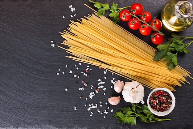 Pasta-ingrediënten en kruiden op zwarte leisteenoppervlak. Bovenaanzicht, plat leggen met kopie ruimte.