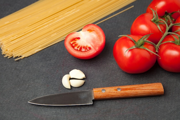 Pasta ingrediënten. Tomaten, spaghetti pasta en knoflook, op donkere grunge achtergrond