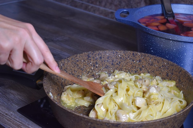 Pasta koken op het fornuis in de keuken thuis. vrouwelijke chef-kok die lunch voorbereidt