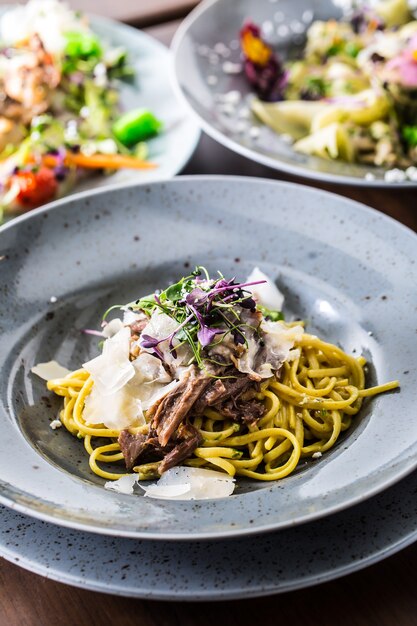 Pasta linguine met gekonfijte eendenborst Parmezaanse kaas en kruidendecoratie.