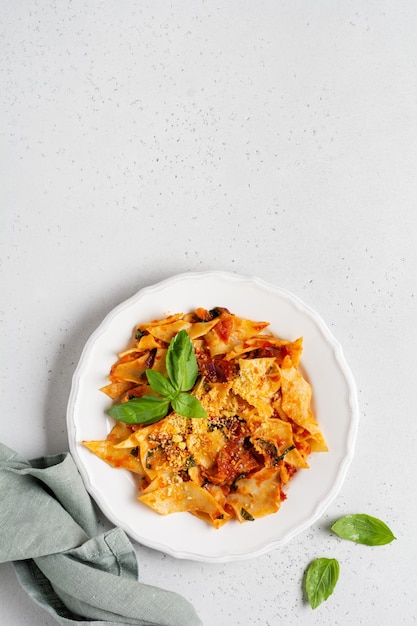 Pasta Maltagliati with classic tomato sauce, parmesan and basil on a rustic concrete