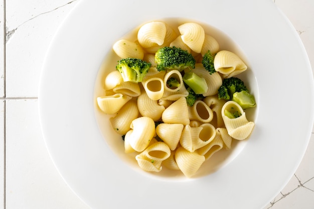 Pasta met broccoli op een witte plaat en een witte keramische achtergrond