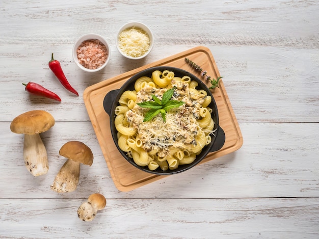 Pasta met cent broodje op een gietijzeren pan op een witte houten tafel.