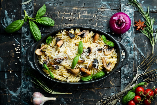Pasta met champignons Parmezaanse kaas en basilicum in een zwarte pan Bovenaanzicht