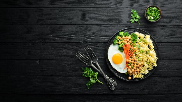 Pasta met groenten en gebakken ei op een zwarte stenen plaat Kom Boeddha Bovenaanzicht Vrije ruimte voor tekst