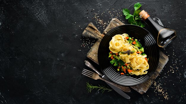 Pasta met groenten noedels bovenaanzicht op een zwarte achtergrond gratis kopieerruimte