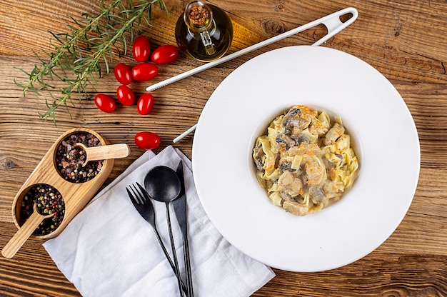 Pasta met kip en champignon met kruiden rozemarijn en tomaten op houten achtergrond