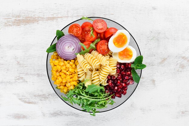 Pasta met mais ei tomaat rucola in een kom Bowl Buddha Bovenaanzicht vrije ruimte voor uw tekst