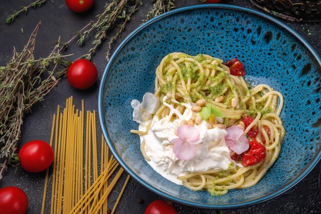 Pasta met strachatella en pestosaus in een blauw bord op een donkere stenen tafel