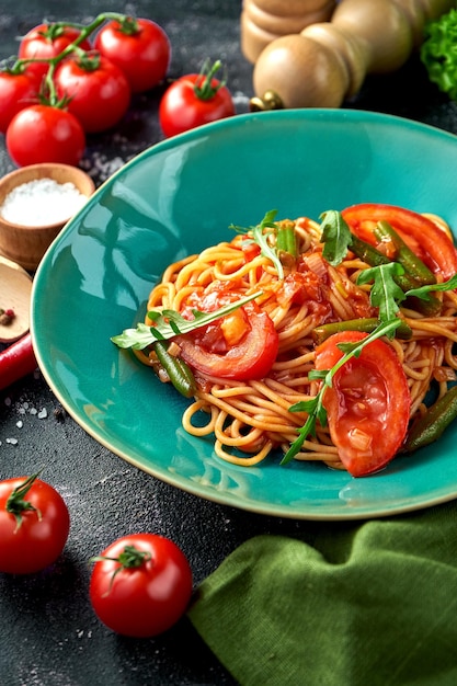 Pasta met tomatenasperges en rode saus in een bord op een donkere achtergrond