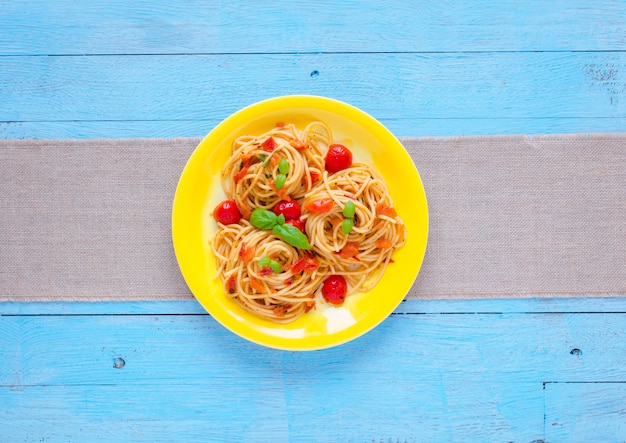 Pasta met tomatensaus en andere componenten op een lichtblauwe houten tafel,