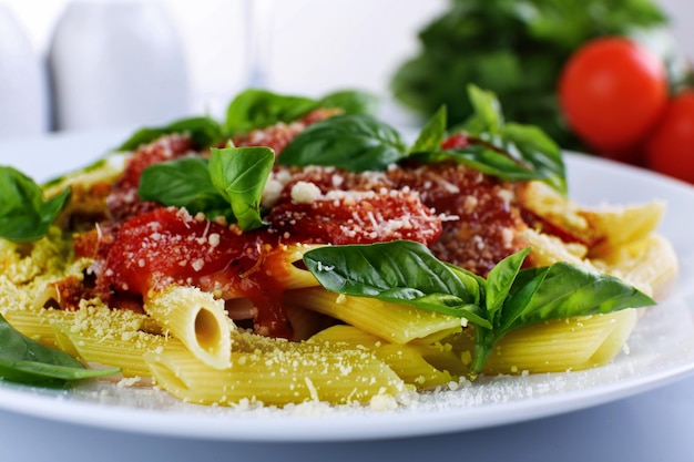 Pasta met tomatensaus en basilicum op tafel close-up