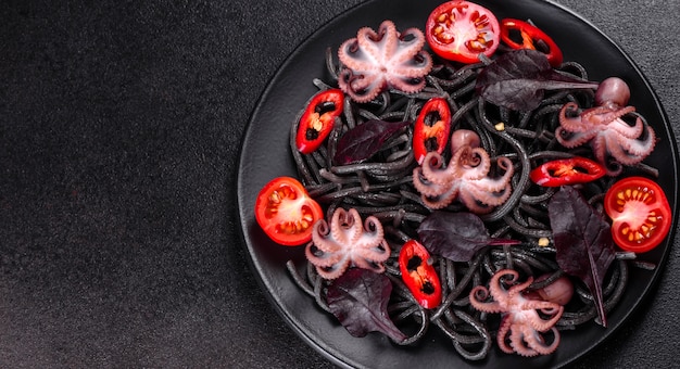 Pasta met zwarte zeevruchten met garnalen, octopus en mosselen. Mediterrane gastronomische gerechten. Zwarte pasta met octopus op een zwarte stenen plaat