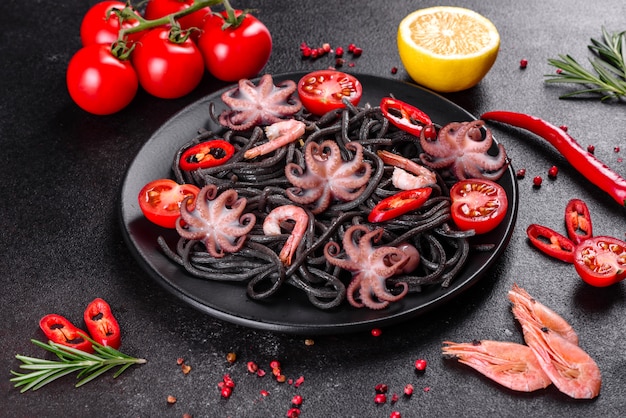 Pasta met zwarte zeevruchten met garnalen, octopus en mosselen. Mediterrane gastronomische gerechten. Zwarte pasta met octopus op een zwarte stenen plaat