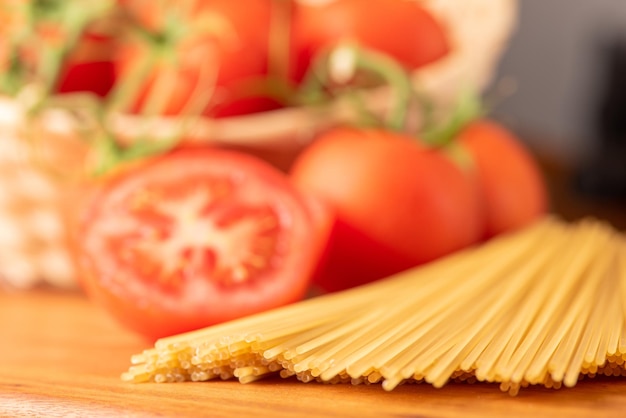 Pasta mooie details van rode tomaten en strengen rauwe spaghetti over rustieke houten selectieve focus