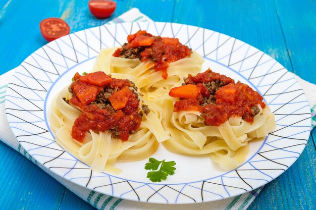 Pasta nest tagliatelle met bolognesesaus en groenten op een bord.