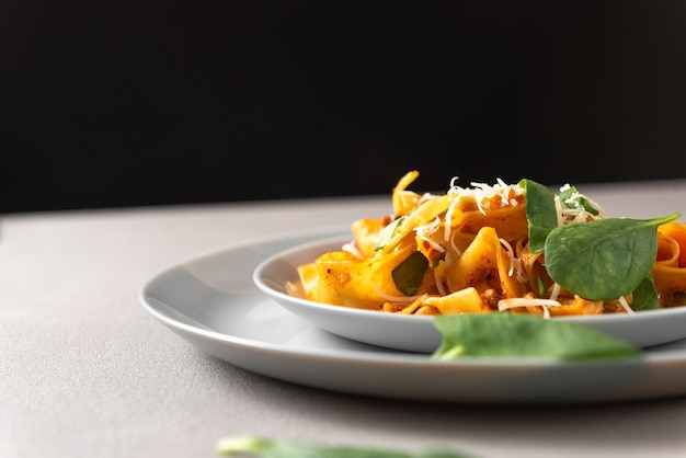 Pasta pappardelle with beef ragout sauce in grey bowl grey background