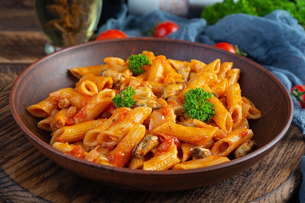 Pasta penne in marinara saus met mosselen, ui en peterselie. Klassieke Italiaanse pasta penne