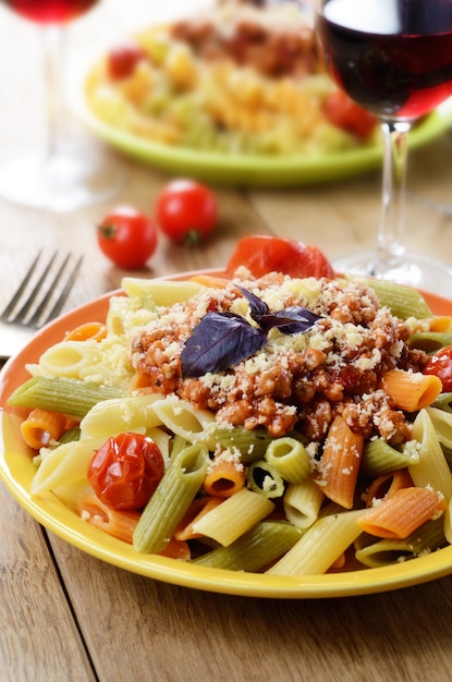 Pasta penne met bolognesesaus geserveerd met rode wijn