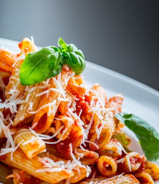 Паста Пенне с томатным соусом болоньезе, сыром пармезан и базиликом. Средиземноморская кухня, итальянская кухня.