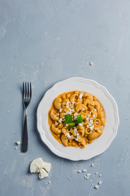 Pasta Pipa de rigat met een saus van kikkererwten en tomaten, besprenkeld met fetakaas en koriander