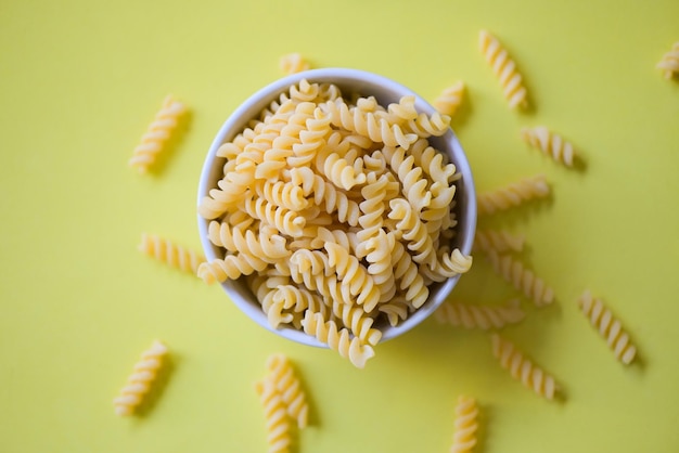 Pasta rauwe macaroni op gele achtergrond close-up rauwe macaroni spiraalpasta ongekookt heerlijke volkoren fusilli pasta voor het koken van voedsel